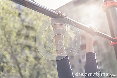 Closeup of a teenager`s hands on a horizontal bar. Pulling on the crossbar. Vintage toning Stock Photo