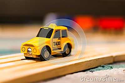 Closeup of a tiny taxi car toy on a wooden table on a blurry background Stock Photo