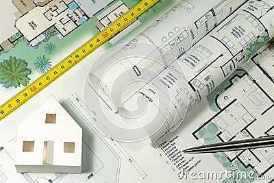Closeup to floor plans, white paper house and measuring yellow tape. Architect drawings, expensive renovation, buildings Stock Photo