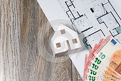 Closeup to floor plans, white paper house, measuring yellow tape and Euros. Architect drawings, expensive renovation, building Stock Photo