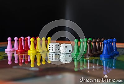 Closeup to a old white dices with color pawns over a board game Stock Photo