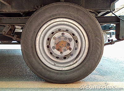 Closeup to Used Tram Trailer Wheel on Yellow Line of Road Stock Photo