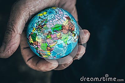 Closeup top view of anonymous male showing small Earth globe in wrinkled hands Stock Photo