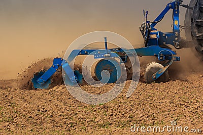 closeup trailer of cultivator raises dust on ploughed field Stock Photo