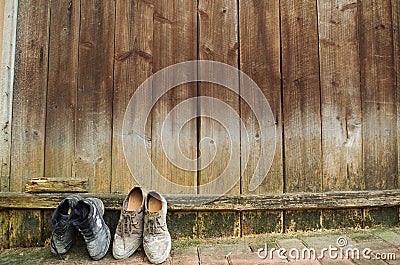 Closeup of two old weathered shoes leaning against a wooden fence Stock Photo