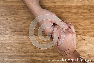 Closeup on two young lovers holding hands at a table Stock Photo