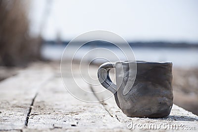 Closeup of unique handmade cup with folk sign with blurred lake on background Stock Photo