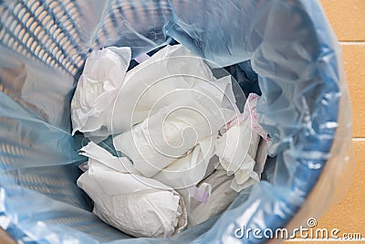 Closeup used sanitary napkin pad wrapped disposed in rubbish bin Stock Photo