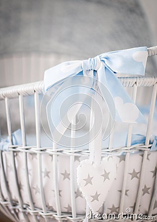 Closeup vertical shot of a white wooden baby basket with a blue bow Stock Photo