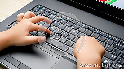 Closeup video of small child hand and finger pressing buttons on laptop keyboard. Child typing word on computer keyboard Stock Photo
