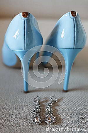 Closeup view of big luxury platinum wedding earrings with diamonds and blue female wedding shoes before the wedding Stock Photo