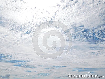 Closeup view of a blue sky mostly covered by puffy white clouds lit up by bright sun rays Stock Photo