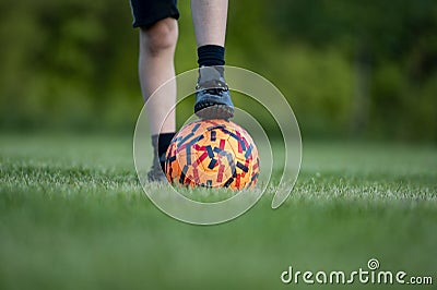 Closeup view of a childs foot in a soccer shoeas on top of soccer ball Stock Photo