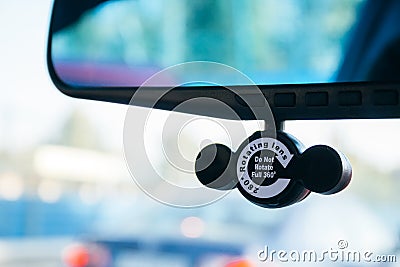 Closeup view of a DVR camera attached to a rearview mirror in a car against a blurred background. A device designed to record Stock Photo