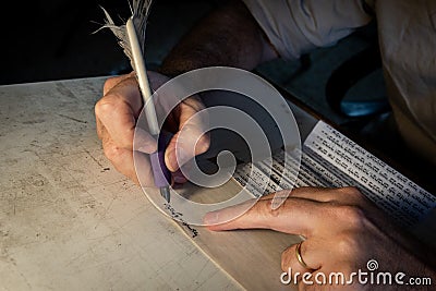 Closeup view of the hands of a Jewish scribe writing the words of the Shema Yisrael prayer on parchment that will be encased in a Stock Photo