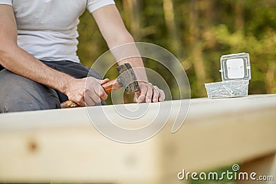 Closeup view of a man using a mallet to hammer a nail in a wooden playhouse Stock Photo