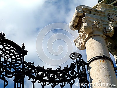 Closeup view of old wrought iron ornamental gate detail. white stone column. Stock Photo