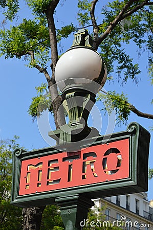 Closeup view of Paris metro sign by day, tree and blue sky in background Editorial Stock Photo