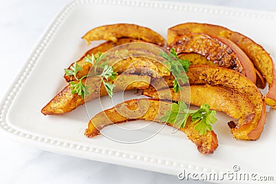 Roasted pumpkin slices with parsley sprigs Stock Photo