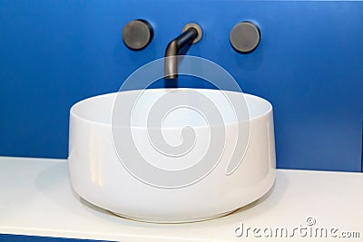 closeup view of white sink with modern simple faucet mounted in blue wall Stock Photo