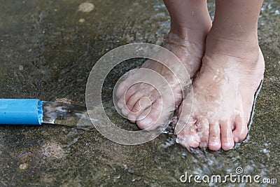 Closeup view of a young child& x27;s feet splashing in water from a r Stock Photo