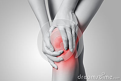 Closeup view of a young woman with knee pain on gray background. Stock Photo