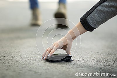 Close up view of young woman picking up lost wallet on city street, empty space Stock Photo