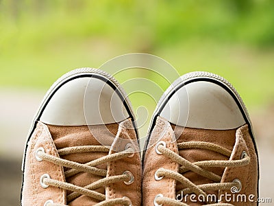 Closeup of vintage soft brown woman sneaker shoes on blur green nature in background. Travel adventure and journey concept Stock Photo