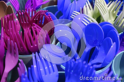 Closeup vivid blue and purple colors plastic ware forks and spoons in plastic cups Stock Photo