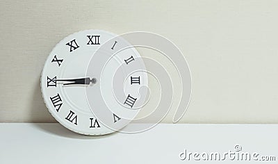 Closeup white clock for decorate show a quarter to nine or 8:45 a.m. on white wood desk and cream wallpaper textured background wi Stock Photo