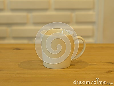Closeup White Cofee Cup on the wooden table with White Brick wall background. Stock Photo