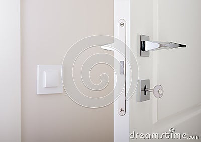 Closeup of white interior doors. Lock with key and chrome door handle Stock Photo