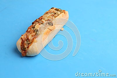 Closeup of a whole delicious hot dog with melted cheese and pepper isolated on a blue background Stock Photo