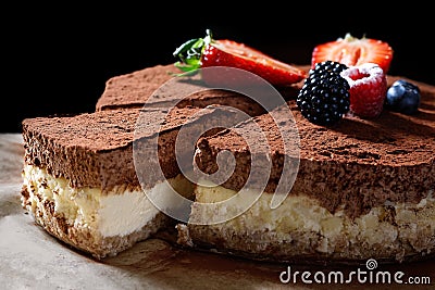 Closeup of whole homemade cheesecake on baking paper with cocoa and fruit topping. A slice cut out Stock Photo