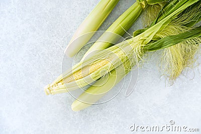 Closeup of Whole Unpeeled and Peeled Baby Corn with Leaves Stock Photo