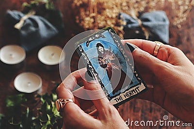 Closeup of wiccan witch holding a small hand painted made up Hermit tarot card in her hands. Stock Photo