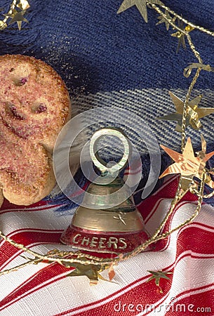 Closeup winter holiday celebration with Cheers on the bell, stars and gingerbread cookie. Background is a blue wool scarf and red Stock Photo