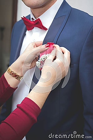 Closeup of a woman adjusting boutonniere on groom suit Stock Photo