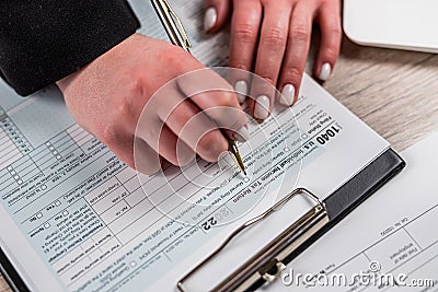 closeup woman filling 1040 tax form at office Editorial Stock Photo