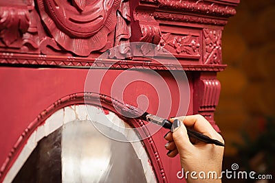 Closeup of woman hand aging carved ornaments of massive wooden cupboard door in pink color. Giving new life to old stuff Stock Photo