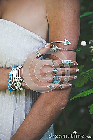 closeup of woman hand and arm with lot of boho style jewrly, rings and bracelets outdoor shot Stock Photo