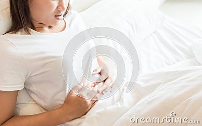 Closeup woman hand holding abdominal with stomach ache lying on Stock Photo