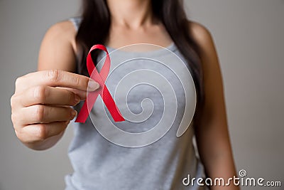 Closeup woman hand holding red ribbon HIV, world AIDS day awareness ribbon. Healthcare and medicine concept Stock Photo