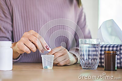 Woman hand preparing to take medicine with glass of water and bottle of pill on desk Stock Photo