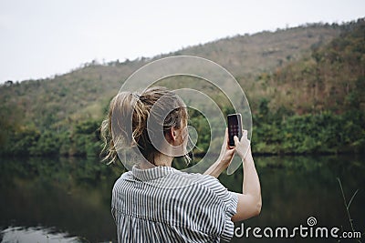 Closeup of a woman hand raising her smartphone up taking a photo of nature travel and tourism concept Stock Photo