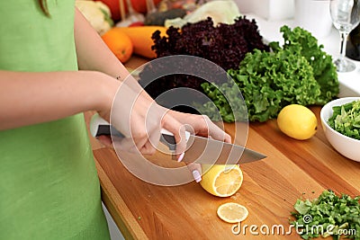 Closeup of woman hands cooking vegetables salad in kitchen. Housewife cuts lemon. Healthy meal and vegetarian concept. Stock Photo