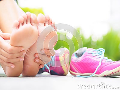 Closeup woman massaging her painful foot while exercising Stock Photo