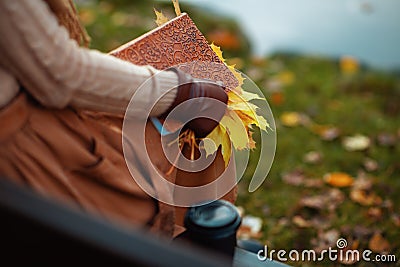 Closeup on woman with notebook, yellow leaves and cup of coffee Stock Photo