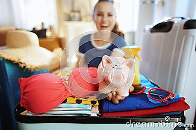 Closeup on woman with piggy bank calculates beach budget Stock Photo