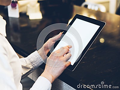 Closeup of a woman pointing finger to an blank display of the tablet with a blue color in a homelike atmosphere on warm bokeh back Stock Photo